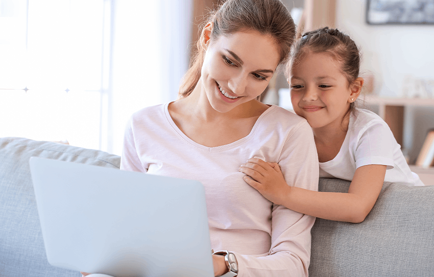 A mother and daughter smiling at a laptop
