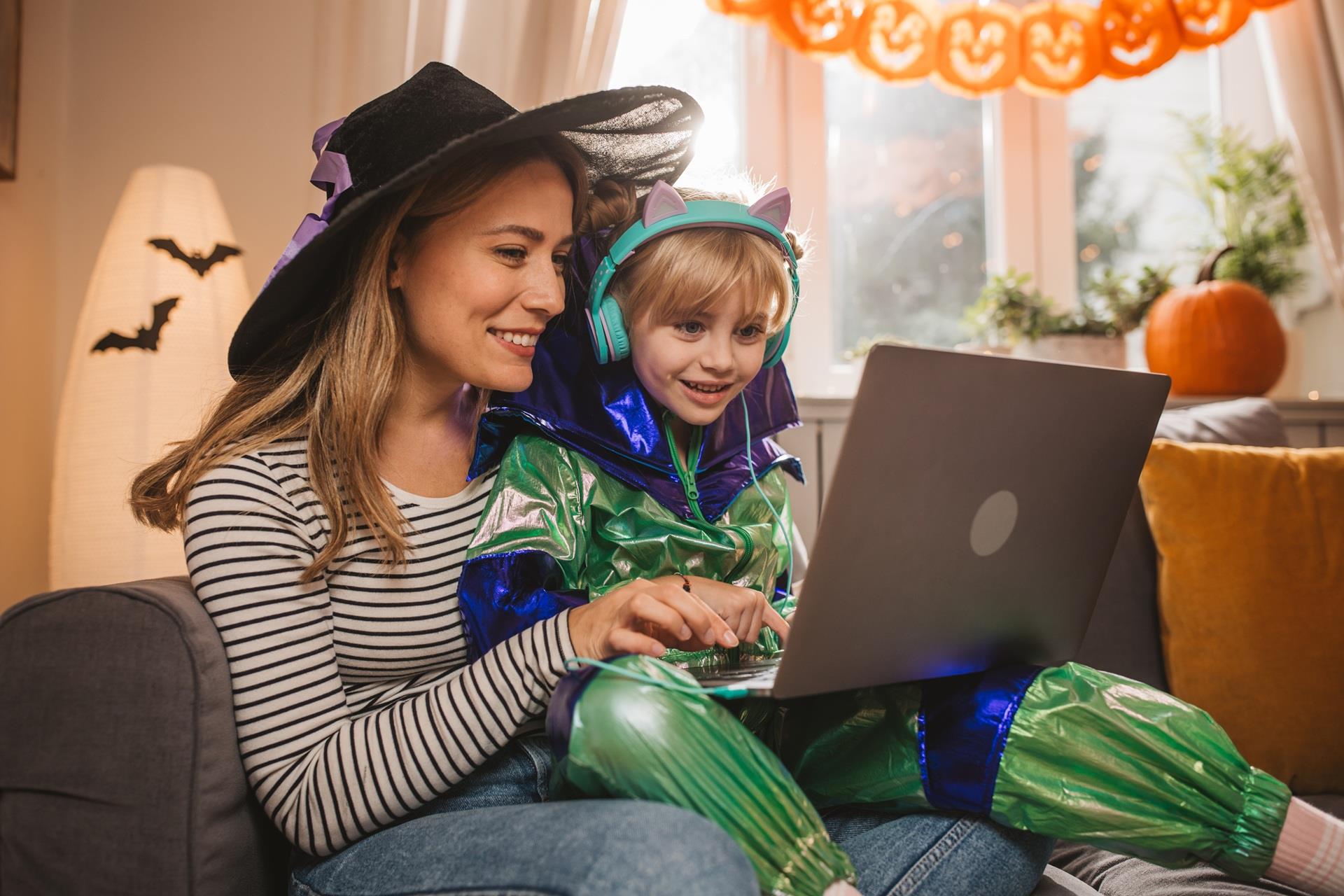 Mom and child in Halloween costumes practicing secure internet browsing on a laptop