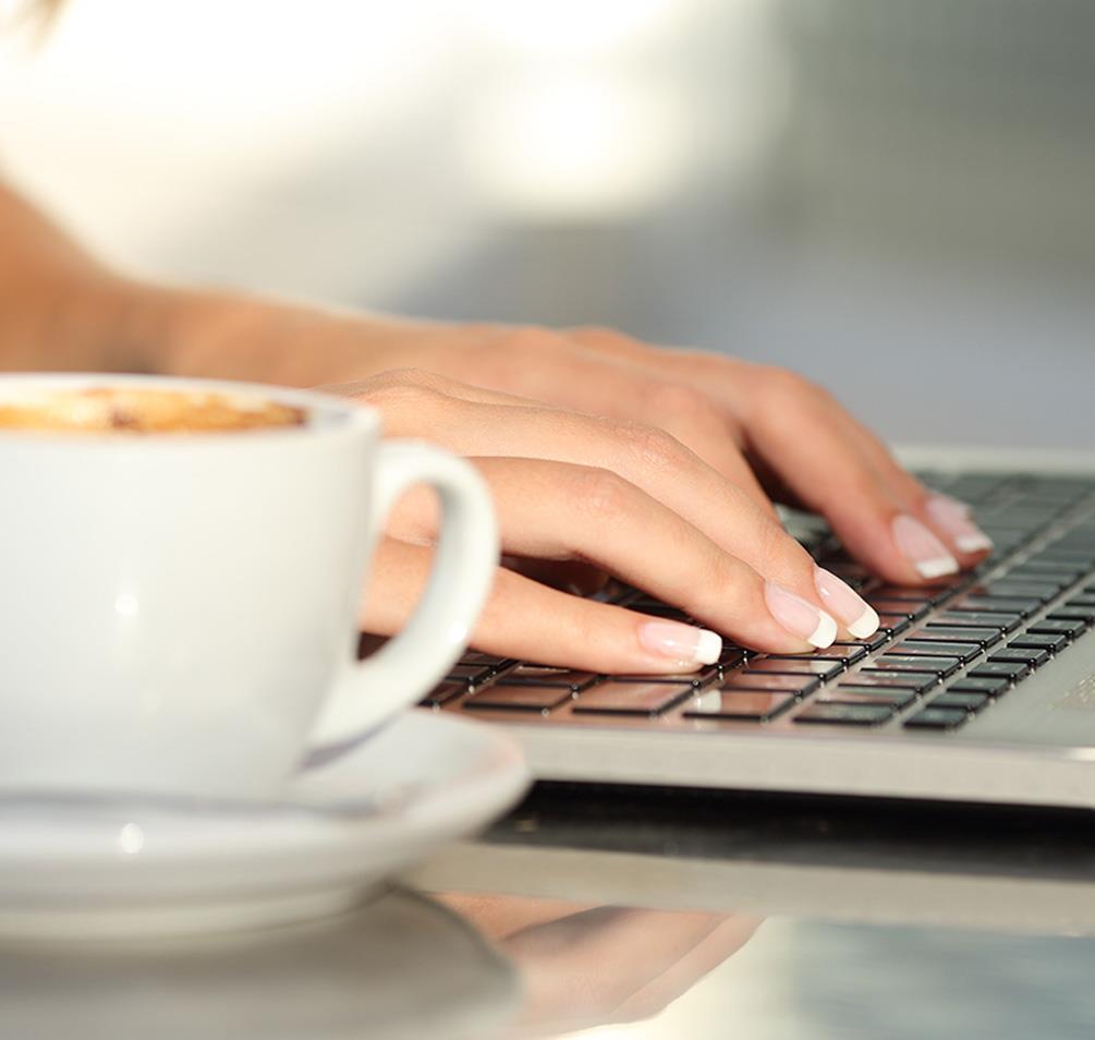 Someone with a cup of coffee using a laptop